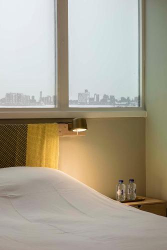 a bedroom with a bed and a window with two bottles at Hotel Light in Rotterdam