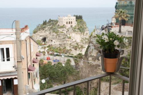 a pot of flowers on a balcony with a view of the ocean at Lo Splendore del Borgo in Tropea