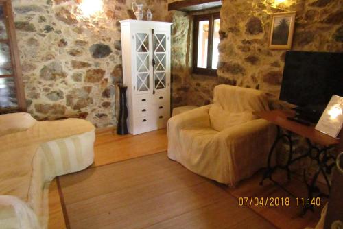 a living room with a couch and a chair and a television at Casa Velha in Figueiró dos Vinhos