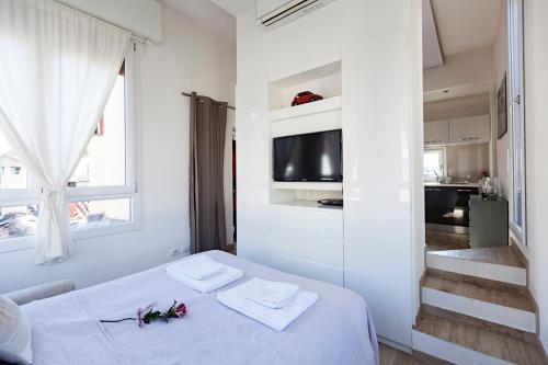 a white bedroom with a bed and a television at Altana Bologna in Bologna