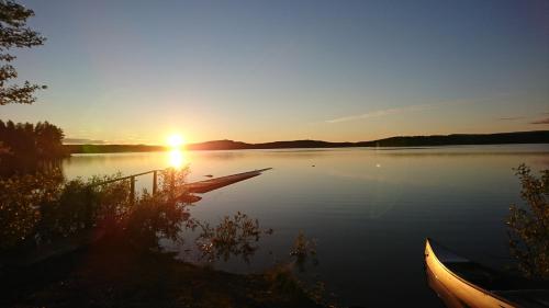 a sunset on a lake with two boats on it at Aurora Camp Kurravaara in Kurravaara