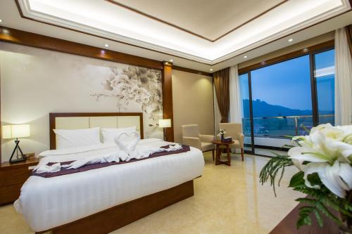 a bedroom with a large bed and a large window at Paksong Danngarm Hotel in Paksong