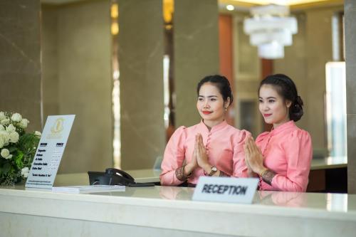 two women are sitting at a desk with their hands in front at Paksong Danngarm Hotel in Paksong