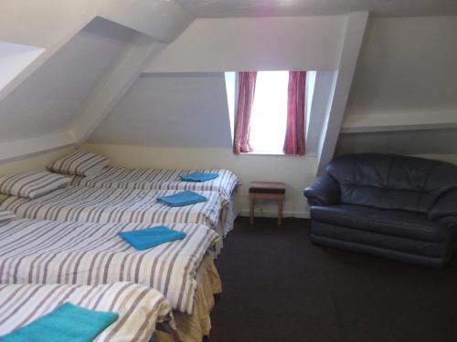 2 camas en una habitación con sofá y ventana en Durham house hotel en Gateshead