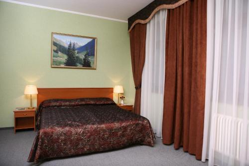 ロストフにあるAZIMUT Hotel Rostov Velikyのベッドルーム1室(ベッド1台付)が備わります。壁に絵が飾られています。