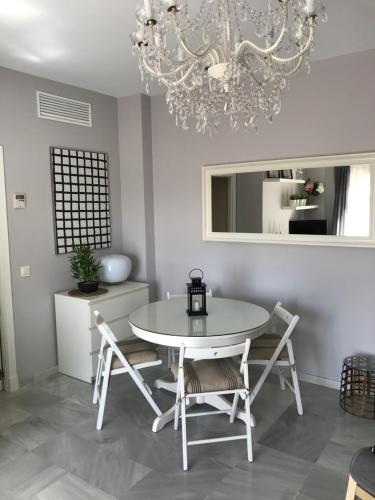 ein Esszimmer mit Tisch und Stühlen und einem Kronleuchter in der Unterkunft Apartamento Costa Ballena in Rota