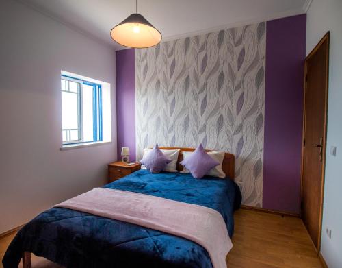 a bedroom with a blue bed with purple walls at Quarto Crescente in Nazaré