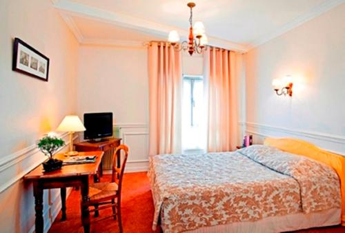 a bedroom with a bed and a desk with a computer at Hostellerie des Trois Pigeons, Paray-le-Monial in Paray-le-Monial