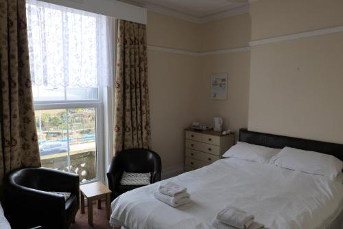 a bedroom with a bed and two chairs and a window at Greystones in Skegness