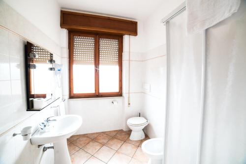 bagno bianco con servizi igienici e lavandino di Hotel da Renato ad Albinia