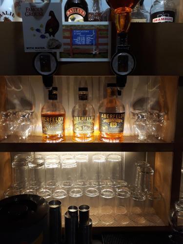 a shelf with alcohol bottles and glasses on it at Ben Lawers Hotel in Lawers