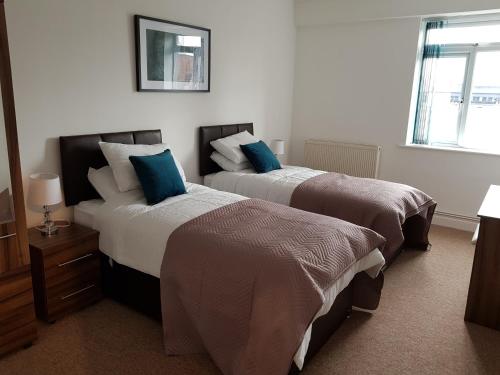 a hotel room with two beds with blue pillows at Norfolk House in Southampton