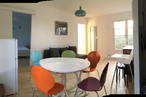 Le Club des Cigales في هييريس: غرفة معيشة مع طاولة بيضاء وكراسي ملونة