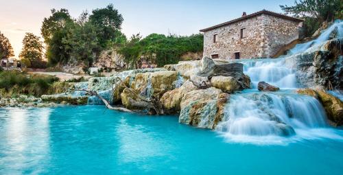 a waterfall in front of a river with a building at Hotel da Renato in Albinia