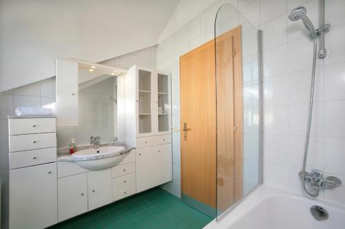 biała łazienka z umywalką i prysznicem w obiekcie City Apartments Mozart w mieście Zell am See
