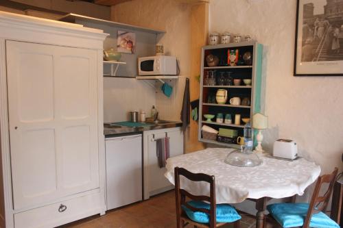 - une cuisine avec une table et une table et des chaises blanches dans l'établissement Le Relais de La Myrpe, à Bergerac