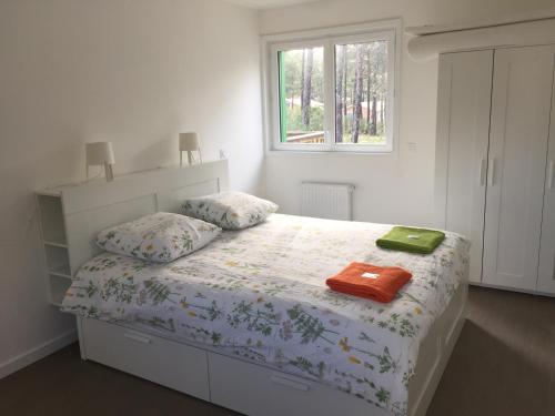a bedroom with a bed with two pillows and a window at Villa Nature in Lacanau-Océan