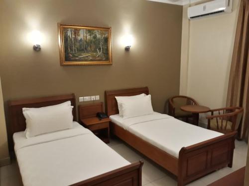 a room with two beds and a painting on the wall at Chelsea Hotel in Dar es Salaam