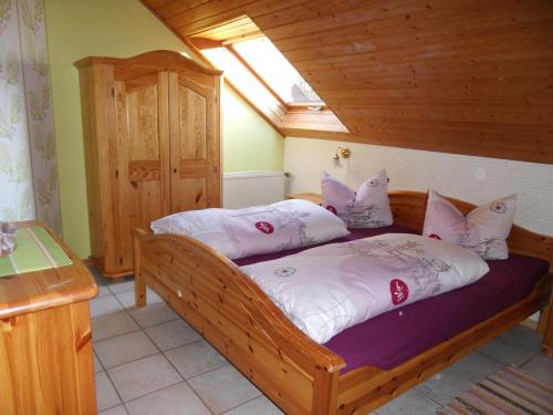 a bedroom with a wooden bed with pink and white pillows at FeWo/GZ Hannelore Müller in Leienfels