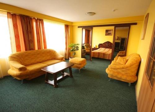 a living room with a couch and chairs and a bed at Hotel Šiauliai in Šiauliai
