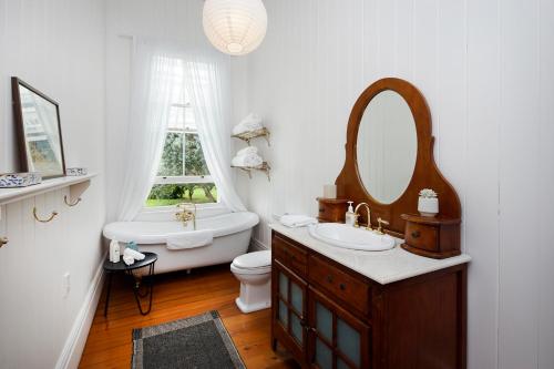 a bathroom with a sink and a toilet and a mirror at Oakura Bay Villa - Stay Waiheke in Te Whau Bay