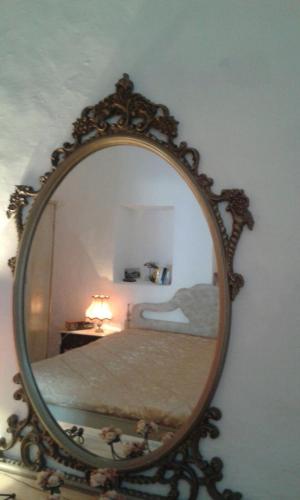 a mirror on a wall with a bed in a room at Trullo Le Tre Sorelle in Cisternino