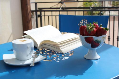 a table with a cup of coffee and a bowl of strawberries at Catarin Comfort Rooms in Castelluzzo