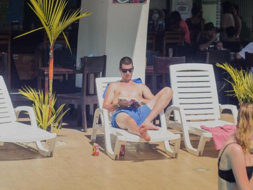 a man sitting in a beach chair with a baby at Room2Board Hostel and Surf School in Jacó