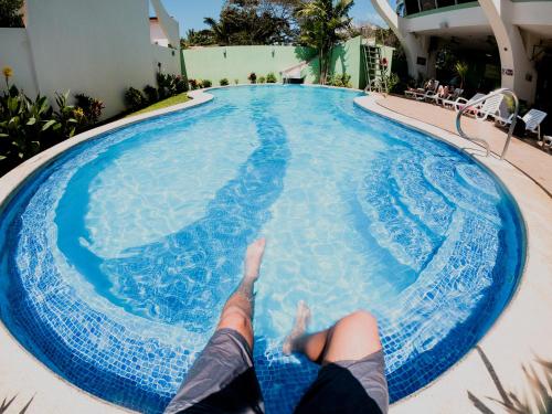 a person laying on the side of a swimming pool at Room2Board Hostel and Surf School in Jacó