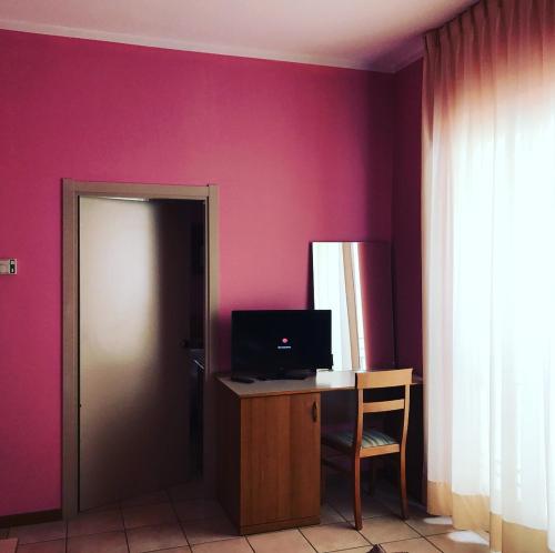Zimmer mit einem Schreibtisch mit einem Computer und einer rosa Wand in der Unterkunft Hotel Pellegrino E Pace in Loreto