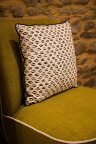 a pillow on a green chair with a stone wall at Villa Des Ursulines in Bayeux