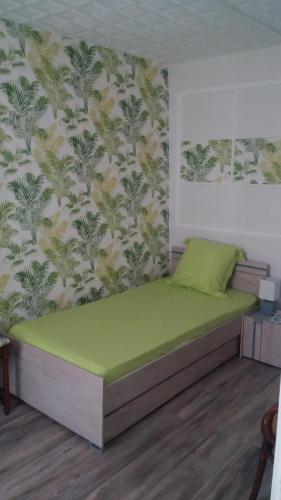 - une chambre avec un lit vert et un mur dans l'établissement Apartment Corneille, à Colmar