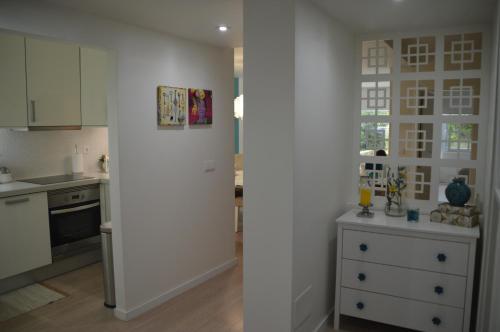 a kitchen with white cabinets and a white refrigerator at Amazing Beach & Pool Apartment with Garden in Sesimbra