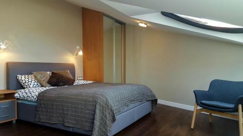 a bedroom with a bed and a blue chair at City Dawn Gate Apartment in Vilnius