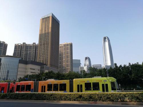 a yellow train in a city with tall buildings at Xizhengjia Apartment Hotel Pazhou Complex in Guangzhou