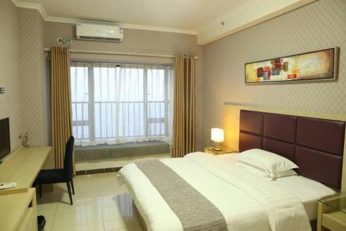 1 dormitorio con cama, escritorio y ventana en Xizhengjia Apartment Hotel Pazhou Complex, en Guangzhou