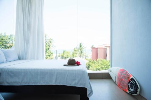 a bedroom with a bed with a hat on it at Room2Board Hostel and Surf School in Jacó
