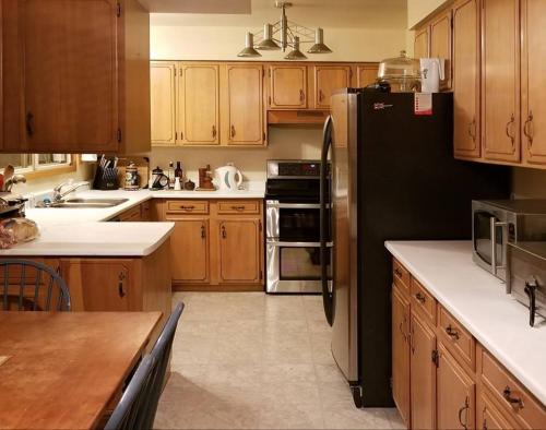 a kitchen with wooden cabinets and a black refrigerator at Beautiful Views on Golf Course in Kingston