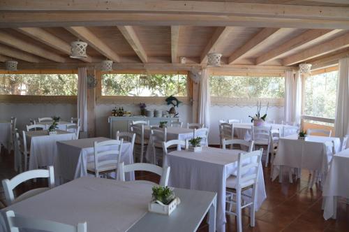 un comedor con mesas blancas y sillas blancas en Hotel Il Timone, en Cugnana