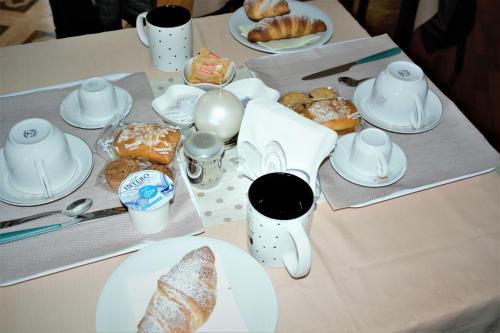 a table topped with plates of pastries and cups of coffee at B&B Kenzia in Olbia