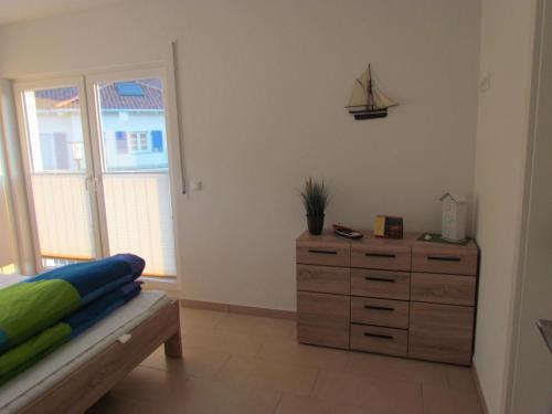 a bedroom with a dresser and a ship on the wall at Haus am Leuchtfeuer A in Peenemünde