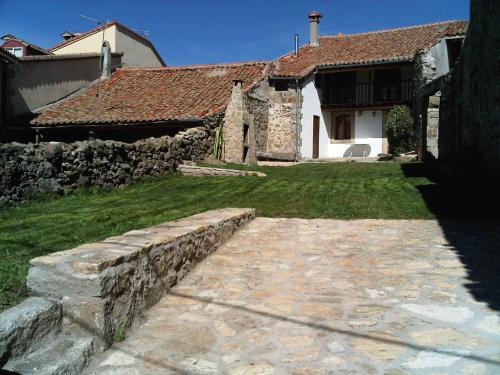 a house with a stone wall and a yard at La Casa del Abuelo in Hoyos del Espino