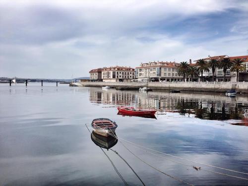a boat sitting in the water in front of buildings at Hotel Bradomin in Villanueva de Arosa