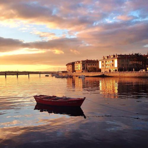 a red boat sitting in the water at sunset at Hotel Bradomin in Villanueva de Arosa