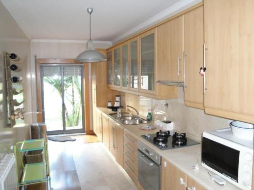 a kitchen with wooden cabinets and a sink at Lirios Nature, Beach & Pool in Fão
