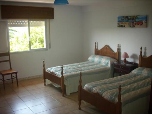 a bedroom with two beds and a chair and a window at Casa Torrre in Rianjo