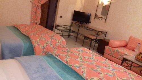 a bedroom with a bed and a couch and a television at Belere Arfoud in Erfoud