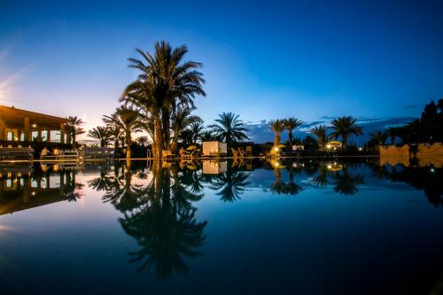 a pool of water with palm trees and a building at Belere Arfoud in Erfoud
