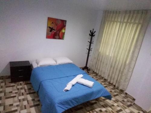 a bedroom with a bed with a blue blanket at La Maison de Lydia in Nazca