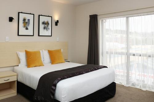 a bedroom with a large bed and a window at The Victoria Hotel Dunedin in Dunedin